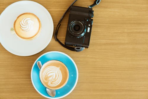 黑色相机和两个咖啡杯碟 · 免费素材图片