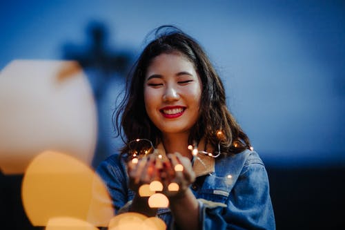 女人拿着灯串的选择性聚焦摄影 · 免费素材图片