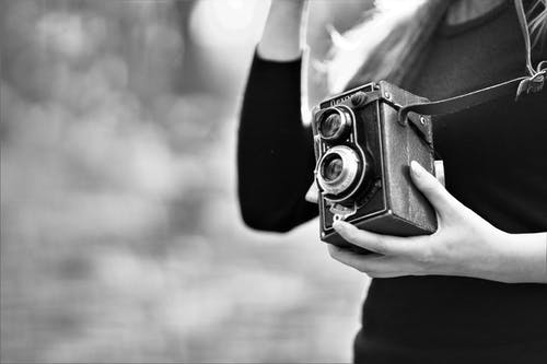 女人拿着老式相机的灰度照片 · 免费素材图片