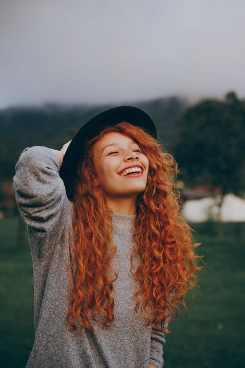 女人微笑着抱着她的帽子 · 免费素材图片