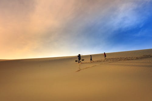 三人在沙滩上行走的剪影摄影 · 免费素材图片