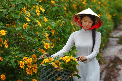 棕色锥帽子和白色长袖连衣裙，拿着自行车把手的女人 · 免费素材图片