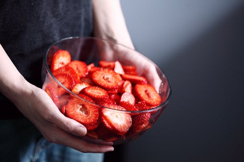拿着碗切片草莓的人 · 免费素材图片