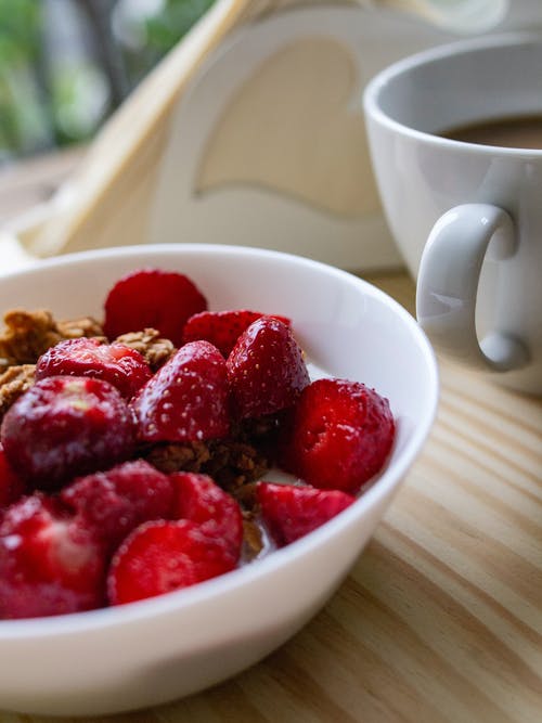 切成薄片的草莓在白色陶瓷碗上的浅焦点照片 · 免费素材图片