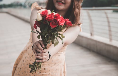 微笑的女人举行的白色和红色玫瑰的特写照片 · 免费素材图片