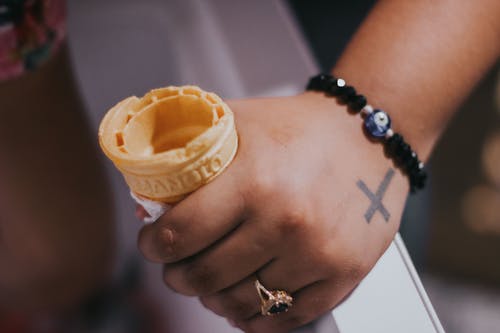 串珠的手链和戒指拿着冰淇淋蛋筒的人 · 免费素材图片