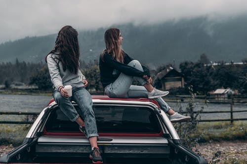 两个女人坐在车顶上 · 免费素材图片