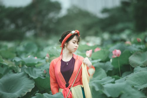 妇女的选择聚焦照片五颜六色的成套装备的，她的眼睛关闭了拿着桃红色花站立在花田中间 · 免费素材图片