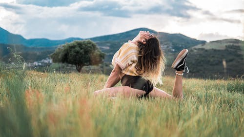 女人坐在绿色的草地上 · 免费素材图片