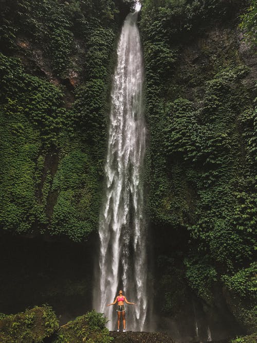 女人站在瀑布前 · 免费素材图片