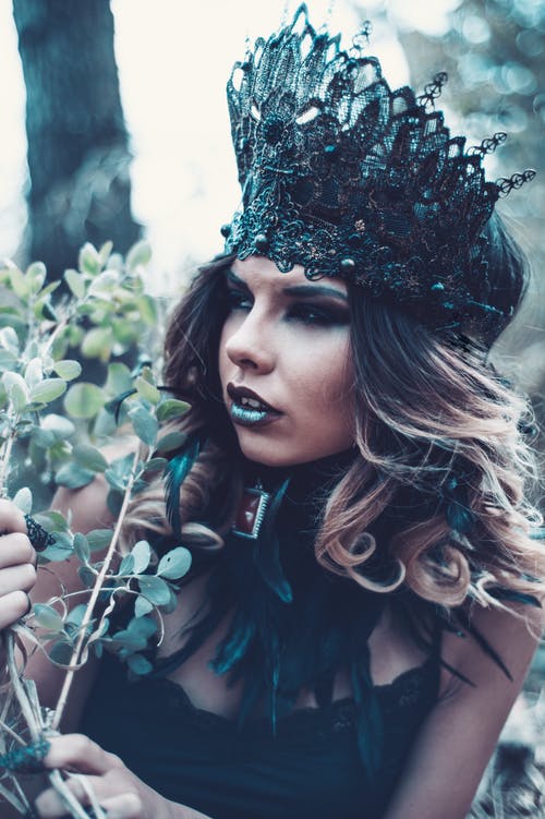 女人穿着绿色的树叶旁边的黑色蕾丝皇冠 · 免费素材图片