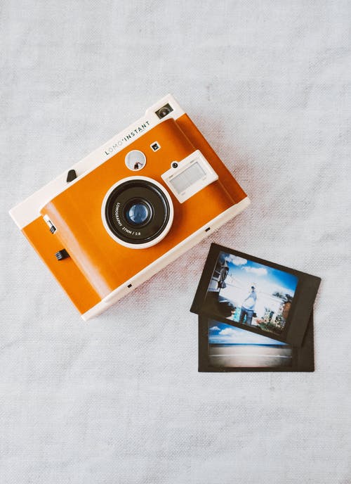 白布上的橙色和白色即时相机 · 免费素材图片