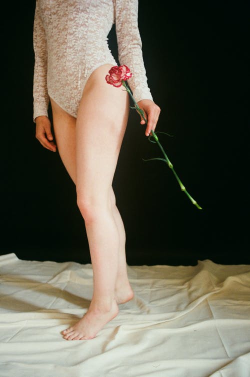 女人穿着白色蕾丝紧身连衣裤拿花 · 免费素材图片