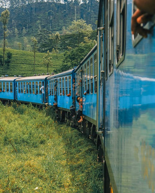 在绿色的田野旁边奔跑的蓝色火车 · 免费素材图片