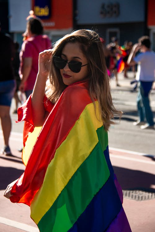 女人抱着彩虹色的旗帜 · 免费素材图片