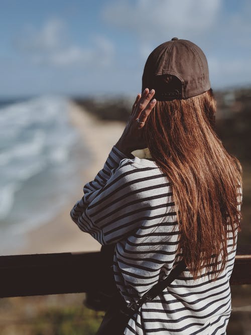女人穿着黑白条纹长袖t恤和黑色帽子望着远方的后视图照片 · 免费素材图片