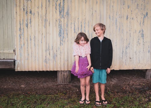 男孩和女孩站在墙上 · 免费素材图片