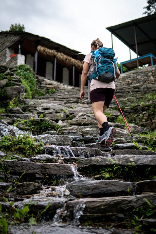 携带黑色和蓝色背包，在岩石楼梯上行走的女人 · 免费素材图片