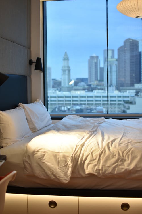 白色枕头在窗户旁边的床上 · 免费素材图片
