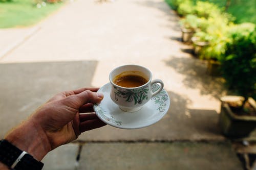 拿着白色陶瓷茶杯的人 · 免费素材图片