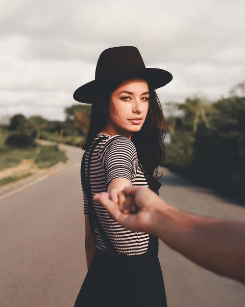 戴黑帽子牵着人的手的女人 · 免费素材图片