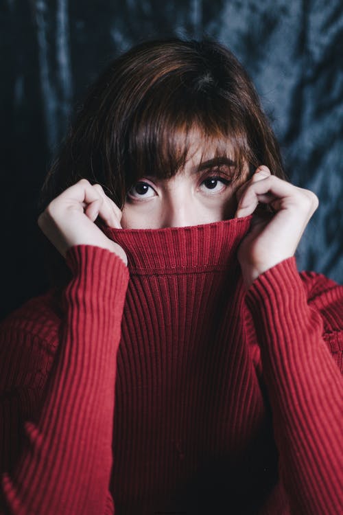 女人捂着嘴，穿着一件红色的毛衣的肖像照片 · 免费素材图片