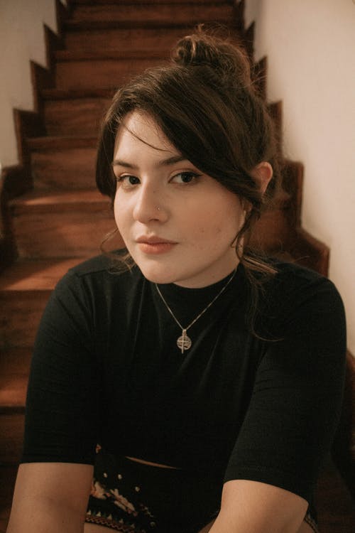 女人穿着黑色的衬衫，坐在楼梯上 · 免费素材图片