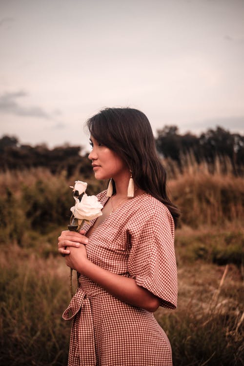 女人在草地上抱着白花 · 免费素材图片