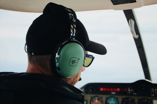 一个人在飞机驾驶舱内戴着耳机和太阳镜的特写 · 免费素材图片