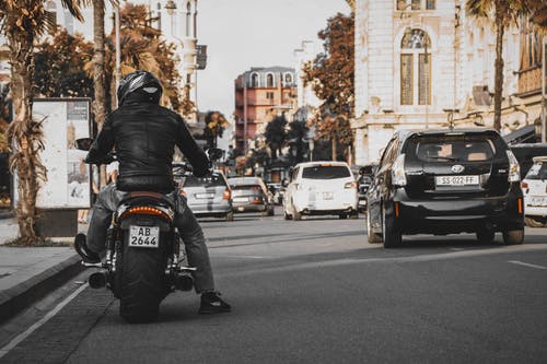 男人穿着夹克和裤子骑摩托车 · 免费素材图片