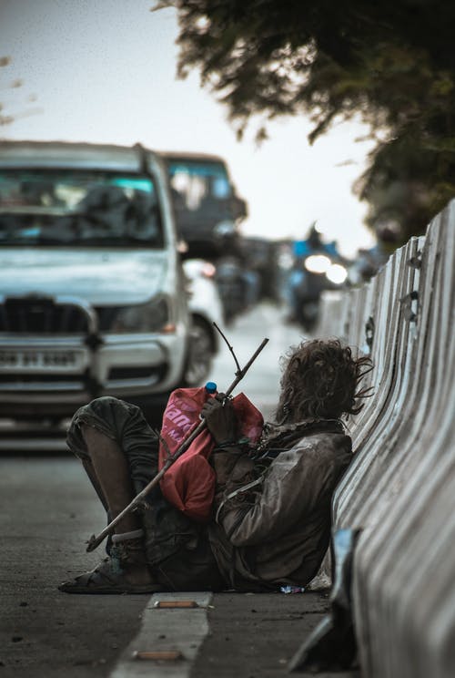 白天坐在路边的男人靠在附近汽车的栏杆 · 免费素材图片