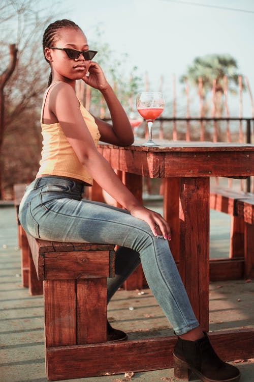 女人坐在棕色的木凳上摆姿势的选择性焦点照片 · 免费素材图片
