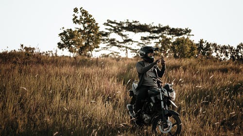黑夹克的人在一辆摩托车在棕色草田 · 免费素材图片