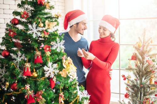 男人和女人站在圣诞树旁边 · 免费素材图片