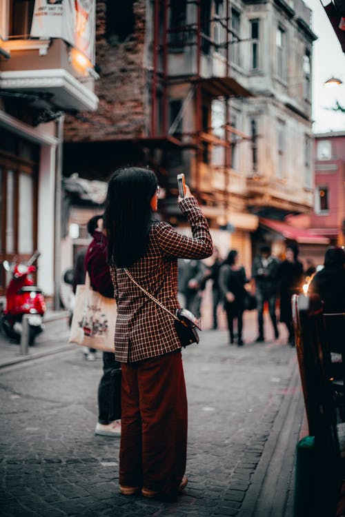 女人站在巷子里拍照的选择性焦点摄影 · 免费素材图片