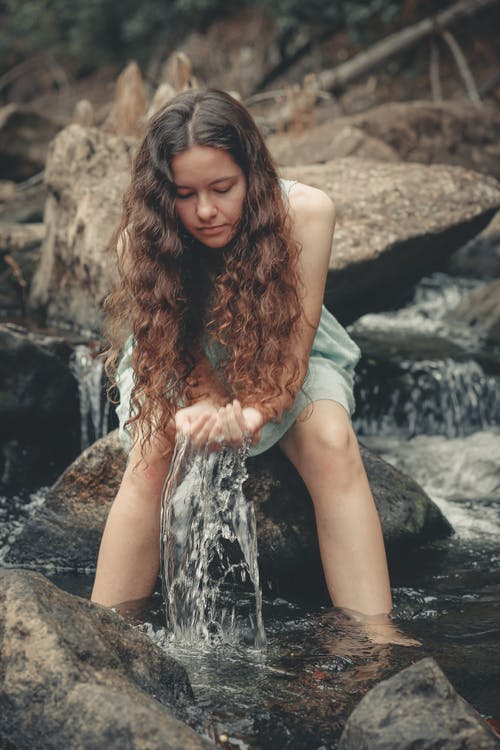 女人坐在河上的岩石 · 免费素材图片