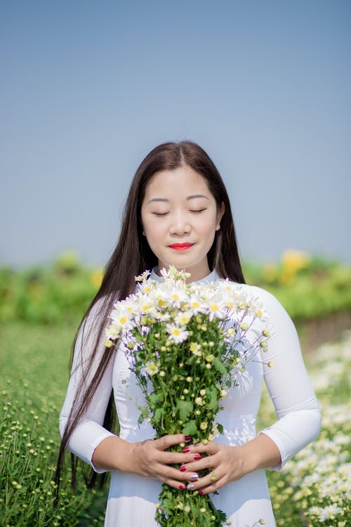 女人拿着白色的花瓣花 · 免费素材图片