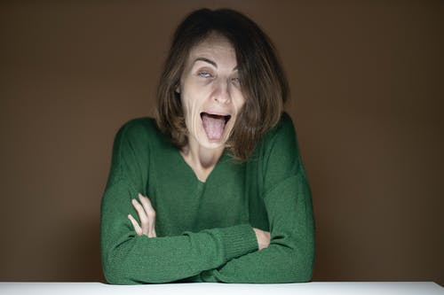 女人穿着绿色的长袖衬衫做鬼脸 · 免费素材图片