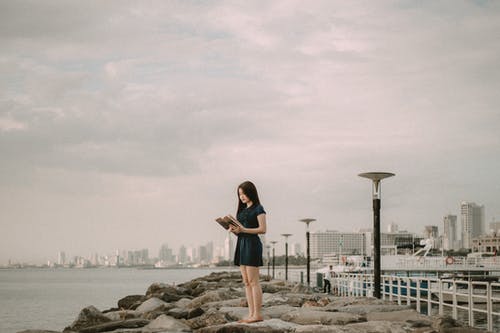 女人在岩石上看书的照片 · 免费素材图片