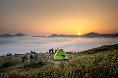 站在绿色帐篷旁边的人 · 免费素材图片