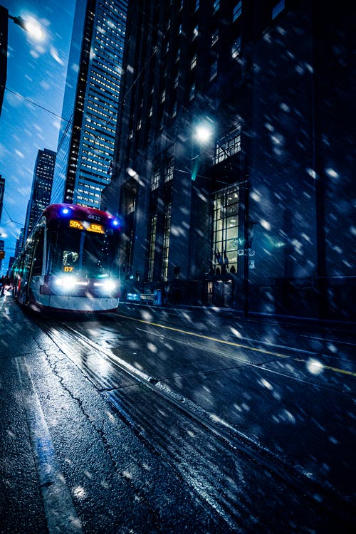 夜间在城市街道上的红色和黄色火车 · 免费素材图片