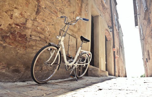 自行车停在狭窄的街道上，对镇上破旧墙壁的老建筑 · 免费素材图片