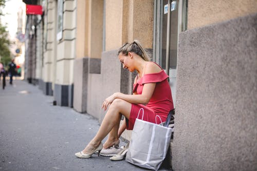 穿着粉红色的连衣裙，坐在门口时穿鞋的女人的照片 · 免费素材图片