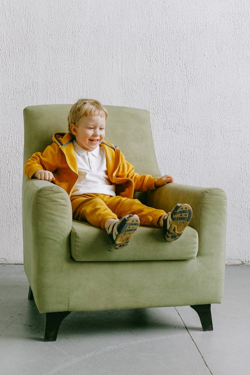 微笑着坐在家里的扶手椅上的小男孩 · 免费素材图片