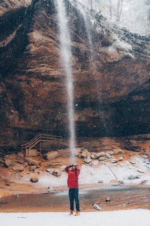 站在瀑布附近的红色外套的人 · 免费素材图片