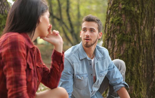 坐在树旁的女人旁边的衬衫的蓝色牛仔纽扣的男人 · 免费素材图片