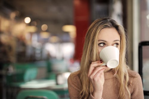 棕色长袖在白色陶瓷杯上喝酒的女人 · 免费素材图片