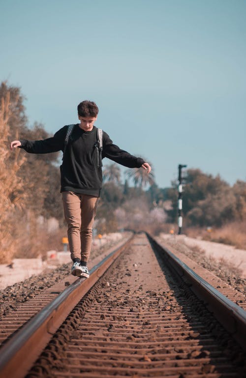 黑色毛衣在火车轨道上行走的人 · 免费素材图片