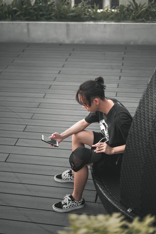 不可识别的民族男子在吸烟时在智能手机上上网 · 免费素材图片