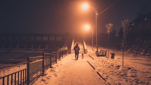 2人在夜间在雪覆盖的田野上行走 · 免费素材图片